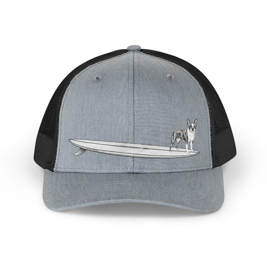 Gray and black trucker hat with a black and white graphic of a Boston Terrier on a surfboard design on a gray background.