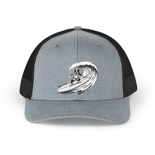 Gray and black trucker hat with a black and white graphic of a Boston Terrier surfing on a big wave with a gray background.