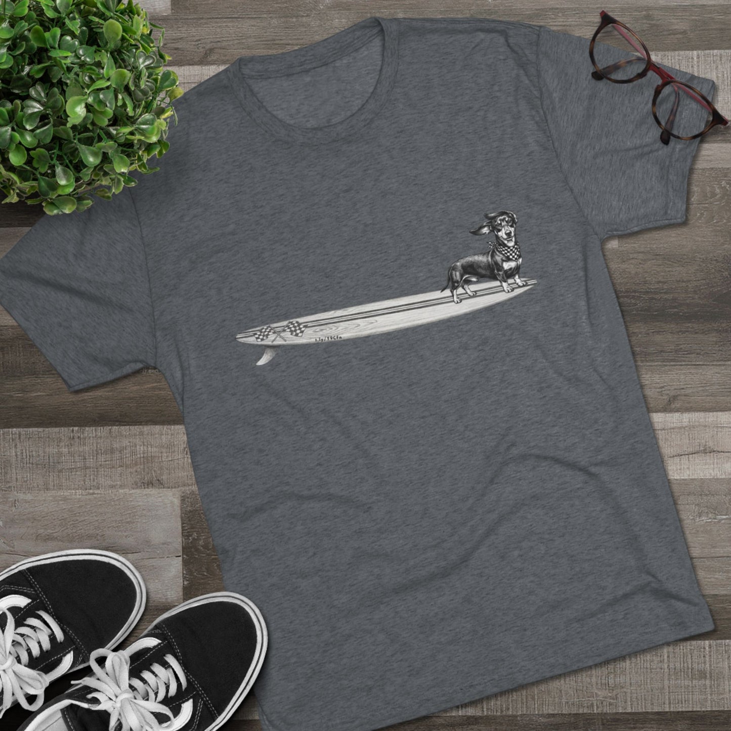 Gray tshirt with a Dachshund dog on a longboard surfboard with racing flags on it. The dog has a checkered bandana around it's neck.