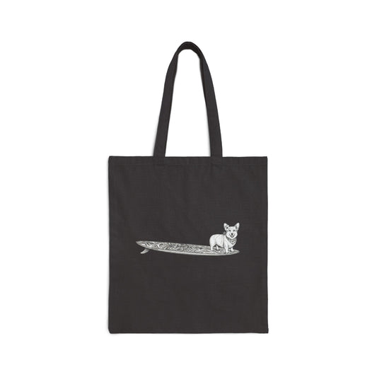 Black tote bag with a Corgi dog with a hibiscus in her ear and a hibiscus bandana and a tiki style surfboard design on a black background
