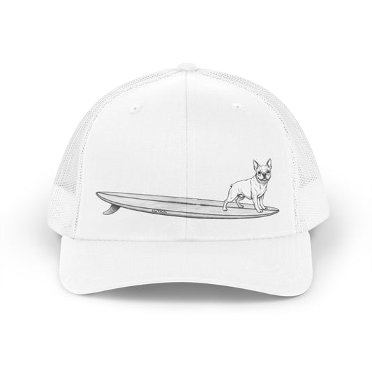 White trucker hat with a black line drawing of a French Bulldog on a long surfboard with a white background.
