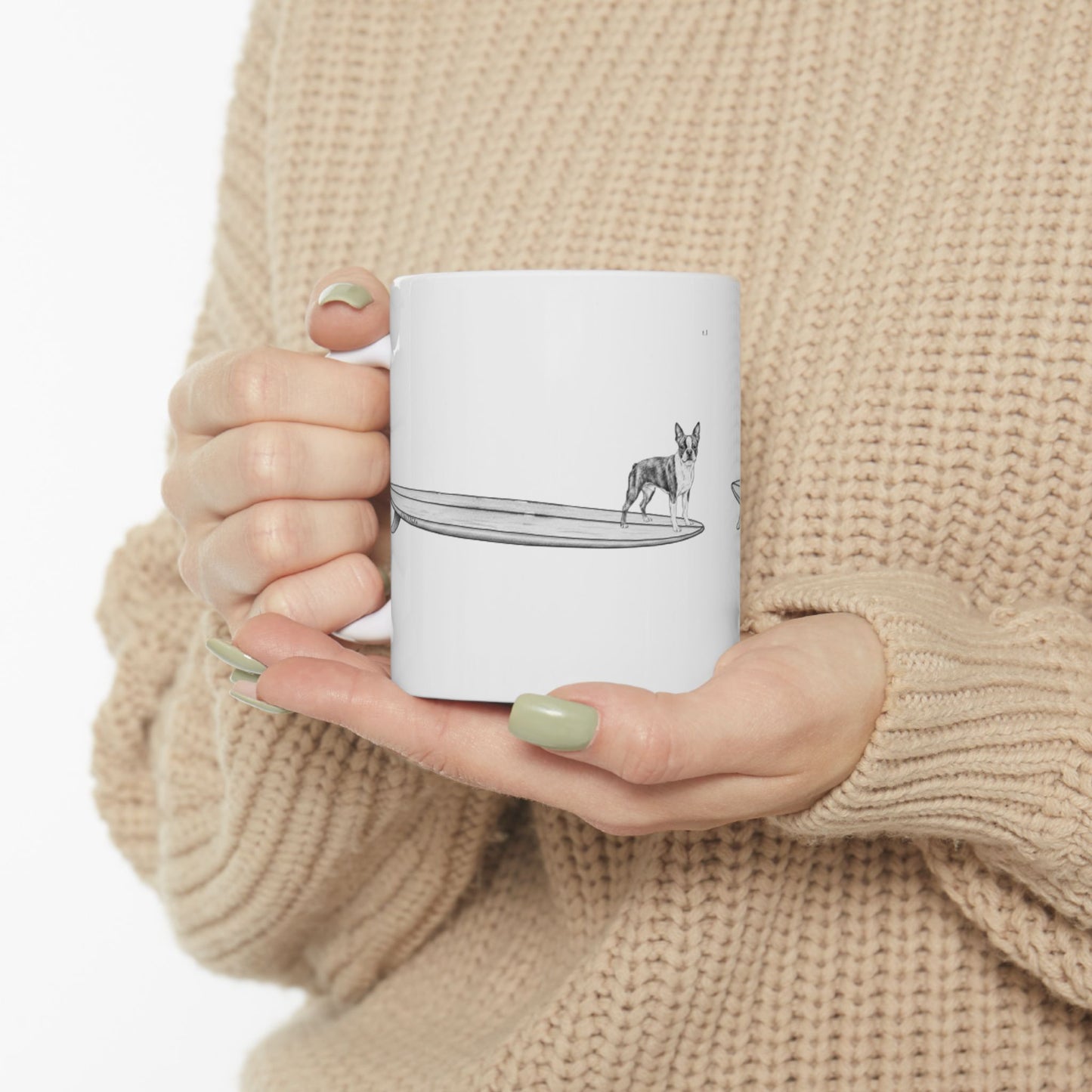 Person holding a White mug with a black and white graphic of a Boston Terrier on a surfboard  on a white background