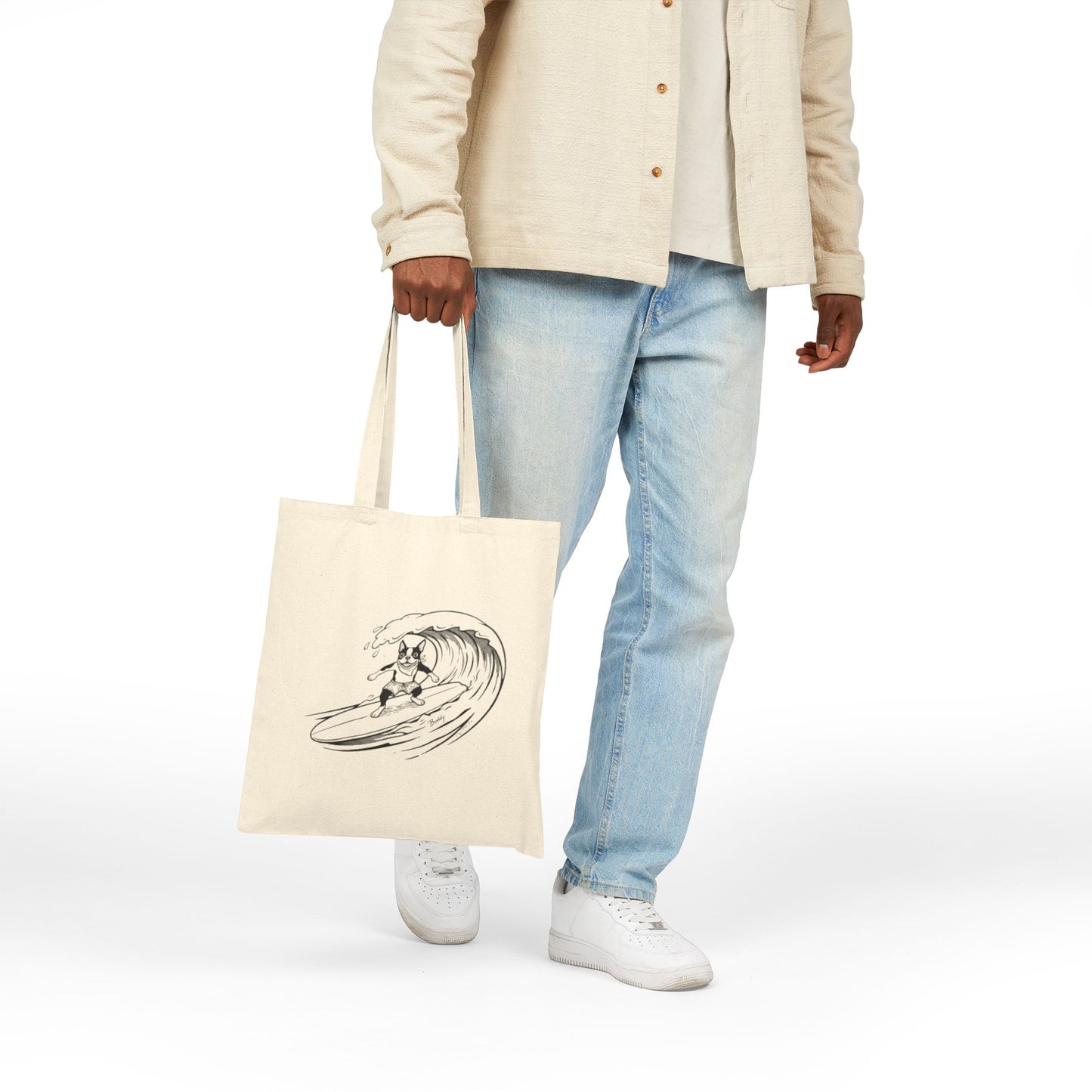 Person holding a Beige tote bag with a graphic of a boston terrier riding a big wave on a longboard with a beige background.