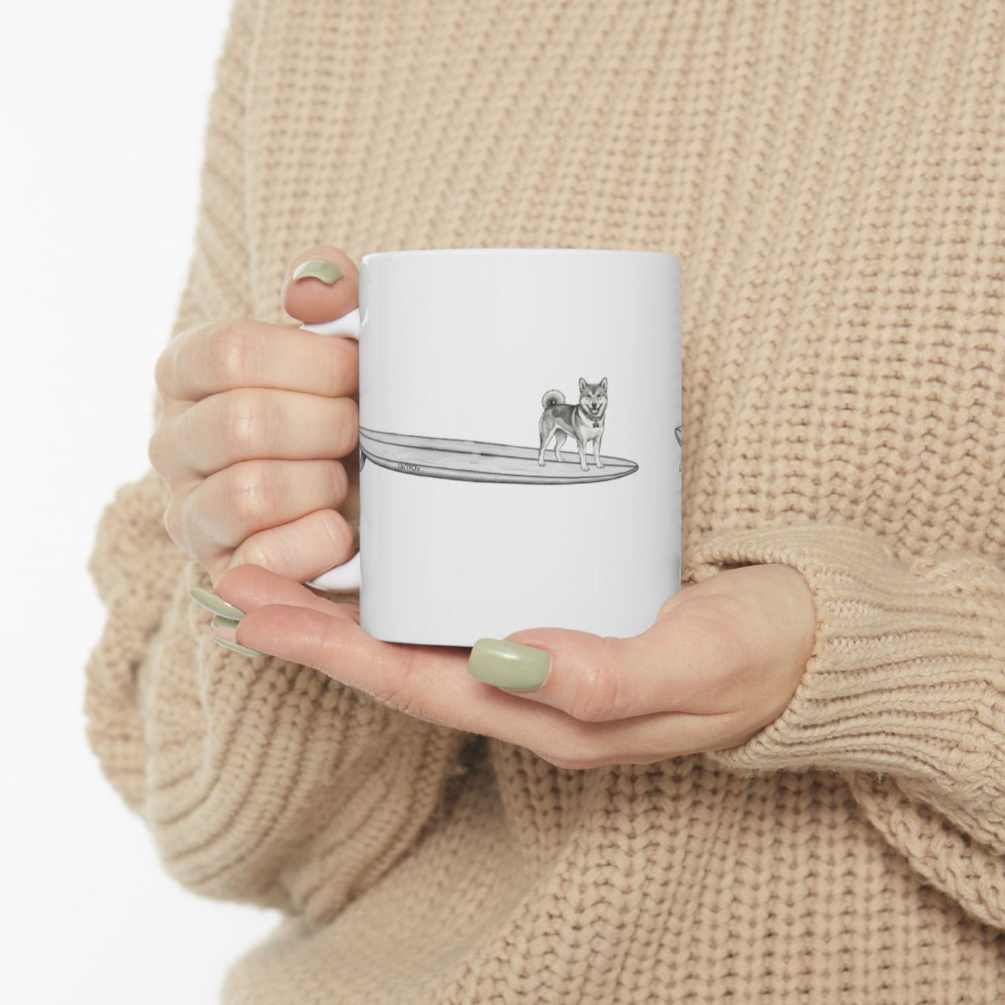 White mug with a design of a Shiba Inu dog hanging twenty on a long surfboard on a white background