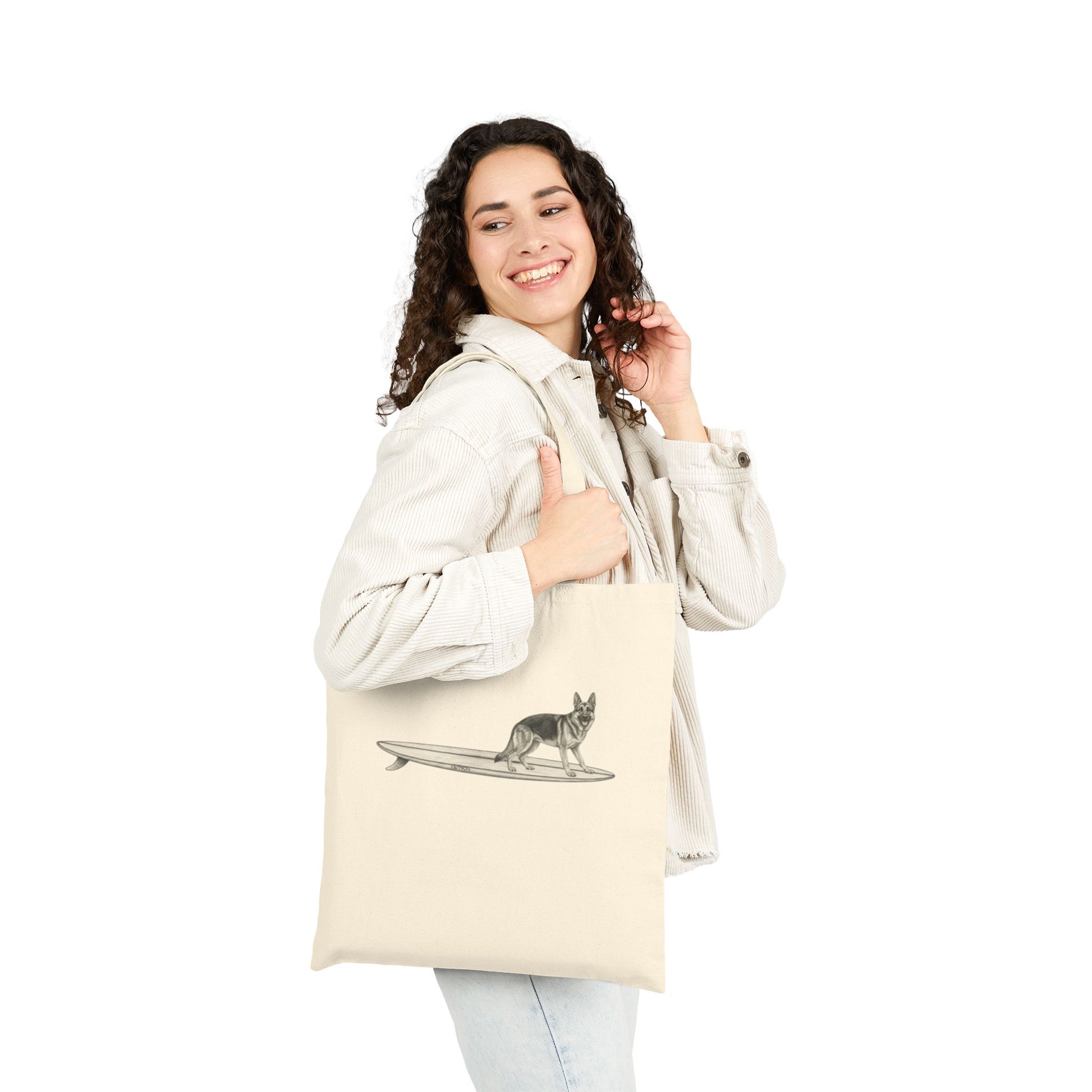 Woman holding a Beige tote bag with a graphic of a German Shepherd dog hanging twenty on a long surfboard on a beige background.