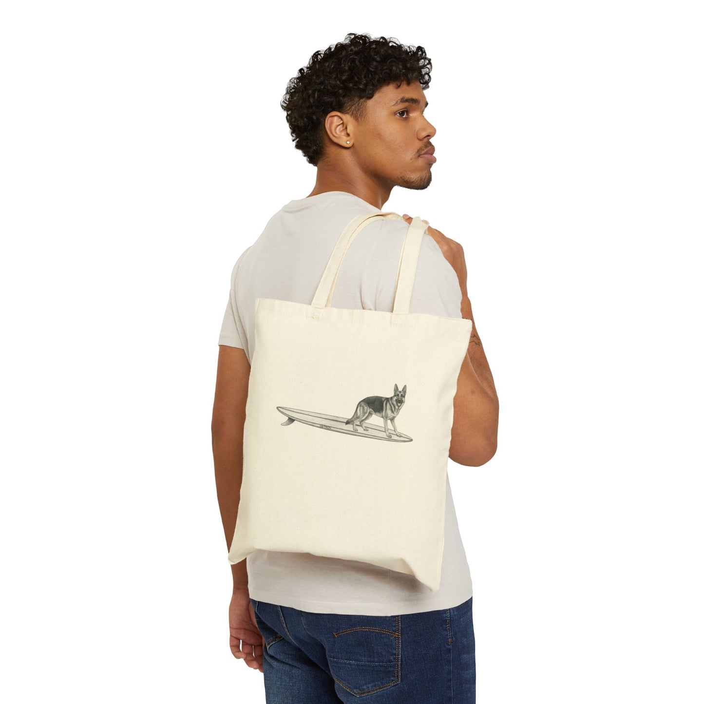 Man carrying a Beige tote bag with a graphic of a German Shepherd dog hanging twenty on a long surfboard on a beige background.