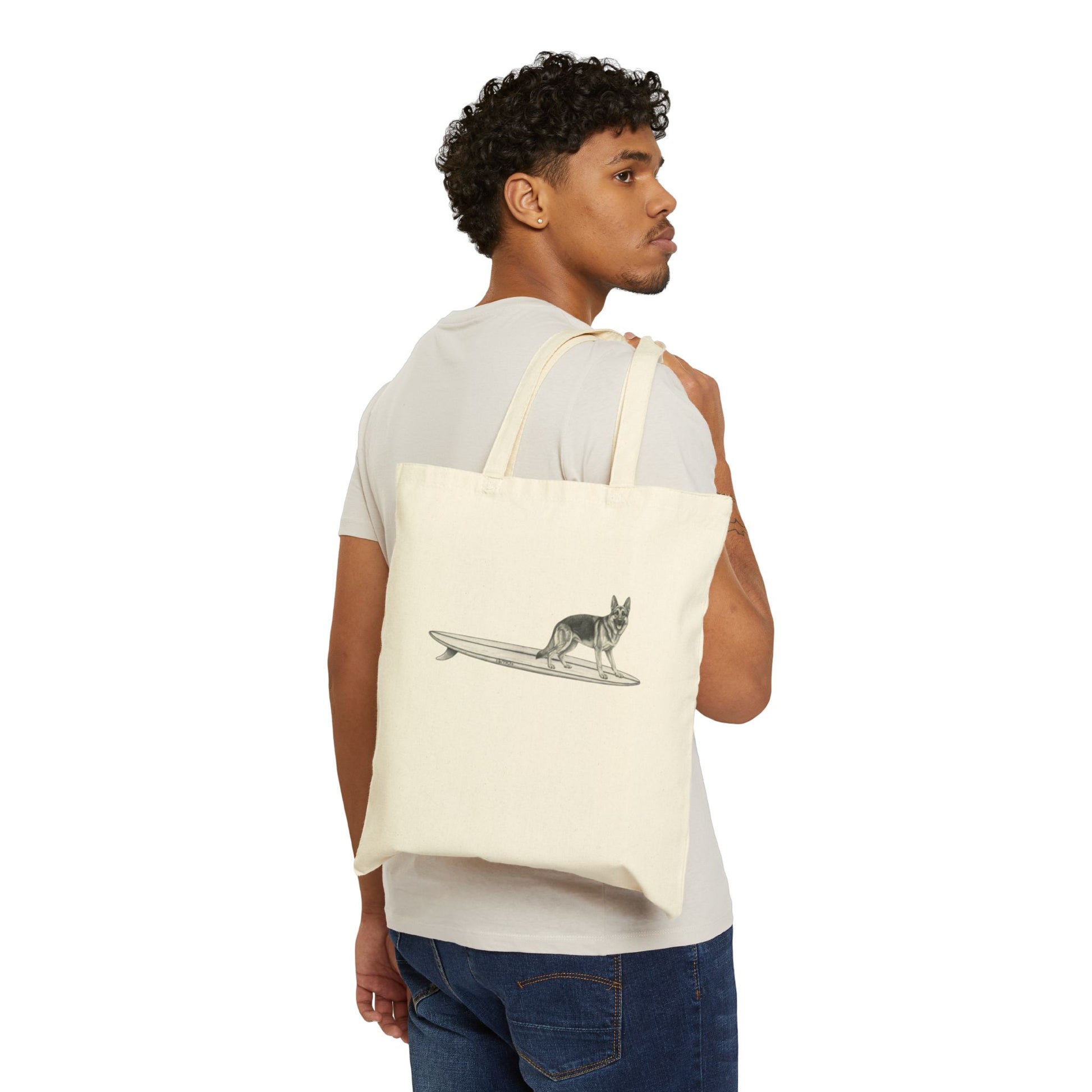 Man carrying a Beige tote bag with a graphic of a German Shepherd dog hanging twenty on a long surfboard on a beige background.