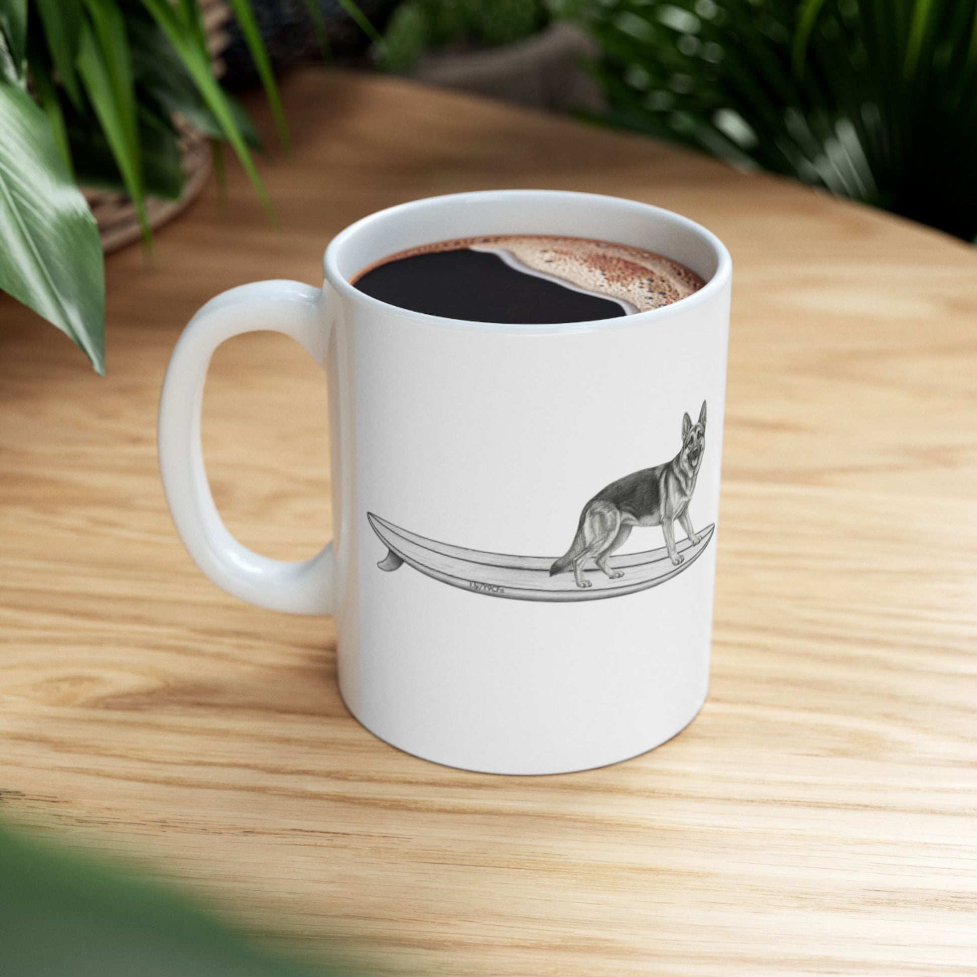 White mug with a graphic of a German Shepherd dog hanging twenty on a long surfboard on a white background.